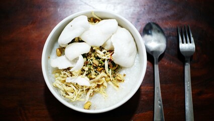 rice porridge with chicken meat and shrimp crackers on wood table