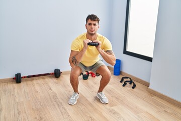 Young hispanic man using weight training at sport center