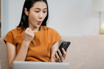 Excited woman work distant on computer talk on cellphone celebrate online win. Happy young female...