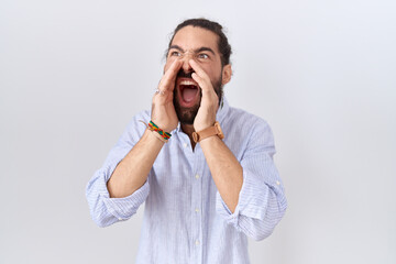 Hispanic man with beard wearing casual shirt shouting angry out loud with hands over mouth