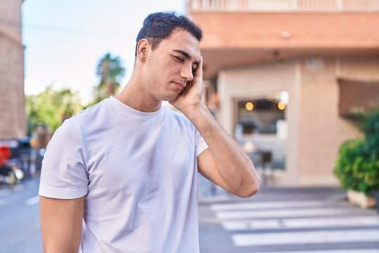 Young hispanic man stressed suffering for headache at street