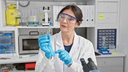 Senior hispanic woman scientist examining a test tube in a laboratory setting