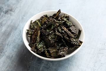 Kale chips, snack in white bowl. Healthy vegetable food.