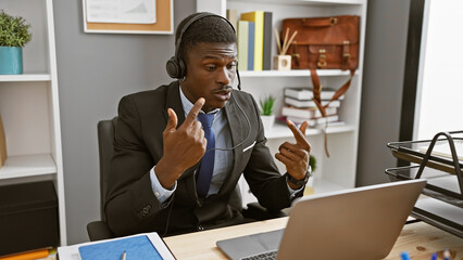 A professional african man in business attire actively communicating during a video call in a...