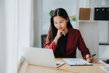 Asian businesswoman in a formal suit in the office with a laptop computer