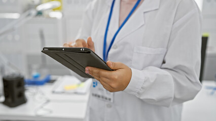 Hispanic woman in lab coat using tablet in laboratory setting