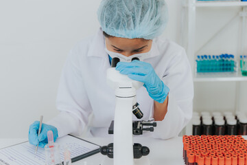 Female doctor taking blood sample tube from shelf with analyzer in lab Technician is holding blood...