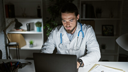 Young hispanic man doctor using laptop working at the clinic