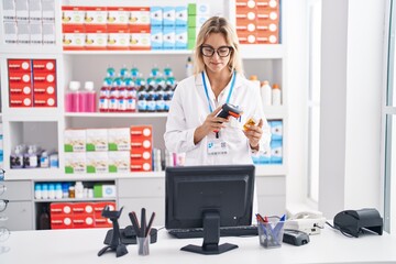 Young blonde woman pharmacist scanning pills bottle at pharmacy