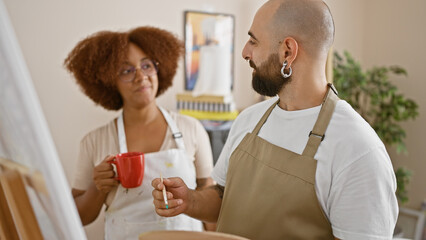 Two smiling artists confidently sipping coffee while drawing in a thriving art studio
