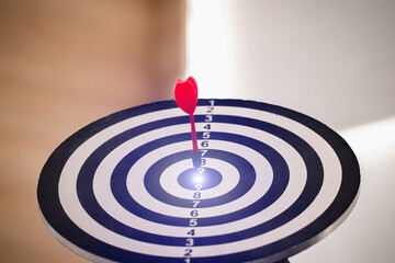 Fototapeta na wymiar Red dart hitting on the target center dartboard, Business targeting or goal success and winner concept, Represent a challenge in business marketing as concept.