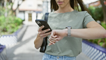Outdoor shot, woman's hands caught texting time countdown on smartphone watch at park amidst city...