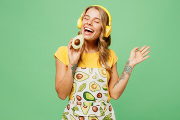 Young housewife housekeeper chef cook baker woman wear apron yellow t-shirt listen to music in...