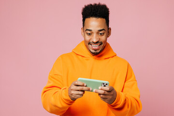 Young man of African American ethnicity wear yellow hoody casual clothes play racing app on mobile...