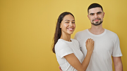 Confident, beautiful couple enjoying a fun, lovely hug, smiling brightly together against an isolated yellow background. two people, standing casual, expressing pure joy and positive lifestyle