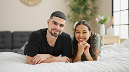 Fototapeta premium Smiling, beautiful couple lying on comfortable bed, relishing their happy relationship and love in the cozy interior of their bedroom.