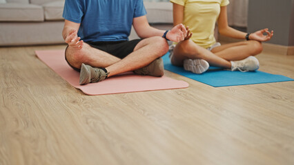 Obraz premium Together at home, two fit hispanic people - a man and woman training yoga, sitting on the floor in their living room, embracing a lifestyle of wellness and balance.
