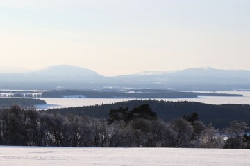 View of the mountains, meadows and the lake. Trees and mountains in winter. Winter landscape in Östersund.

