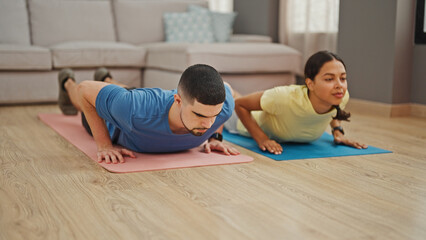 Fototapeta na wymiar Beautiful couple showcasing power and love, training together with indoor push up workout at home