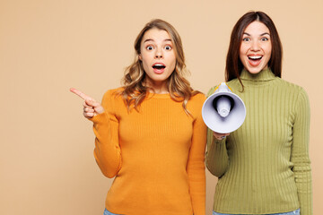 Young friends two women wear orange green shirt casual clothes together hold megaphone scream...