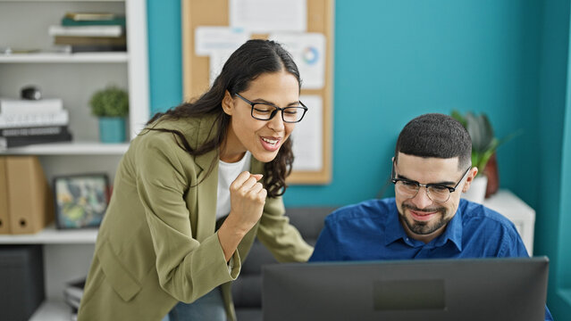 Celebrating success, two energetic workers, a man and woman, rejoice at their work triumph on computer in the office.