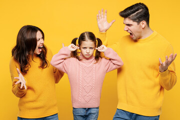 Young sad naughty parents mom dad with child kid girl 7-8 years old wearing pink knitted sweater casual clothes spread hands scream cover ears isolated on plain yellow background. Family day concept.