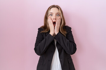 Young caucasian business woman wearing black jacket afraid and shocked, surprise and amazed expression with hands on face