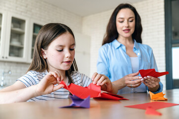 Selective focus on kid holding piece of paper and folding origami bird