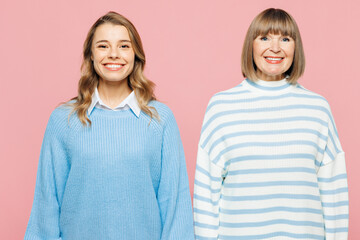Elder smiling cheerful parent mom 50s years old with young adult daughter two women together wearing blue casual clothes look camera isolated on plain pastel pink light background. Family day concept.