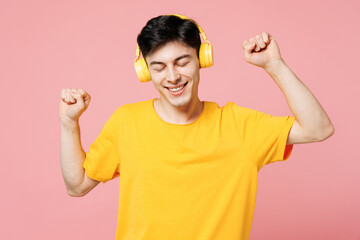 Young Caucasian man he wears yellow t-shirt casual clothes listen to music in headphones raise up...