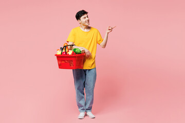 Young Caucasian man he wears yellow t-shirt casual clothes shopping hold in hand basket with food...