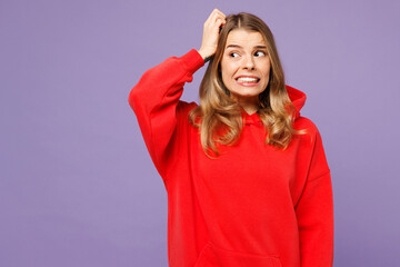 Young puzzled mistaken sad blonde woman she wearing red hoody casual clothes scratch hold head look...
