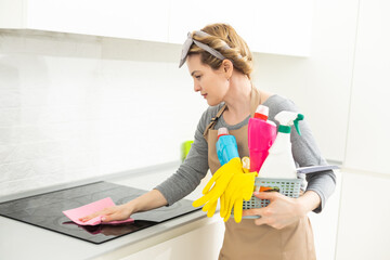 Attractive woman cleaning furniture in kitchen with a rag