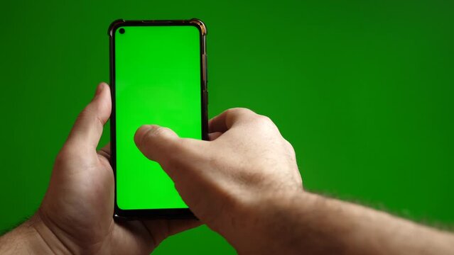 Green screen smartphone scrolling sideways in hand on green background.