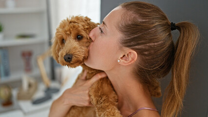 Young caucasian woman with dog kissing on bed at home