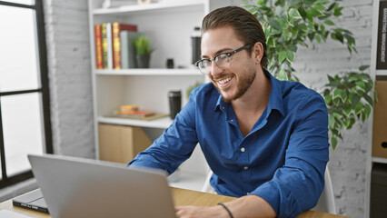 Young hispanic man business worker using laptop working at the office