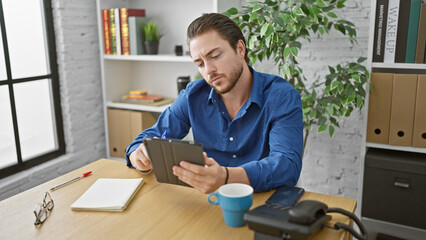 Young hispanic man business worker using touchpad thinking at the office