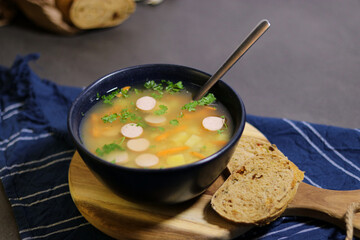 Yellow peas soup with cute sausage in a blue bowl with slices of olive bread