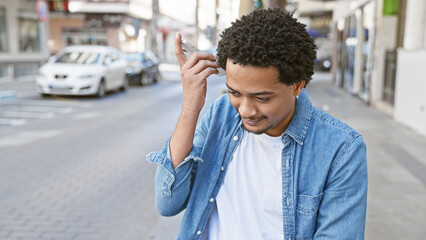 Handsome adult man listening to voicemail on smartphone in city street setting