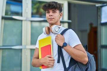 Young hispanic teenager student smiling confident holding books at university