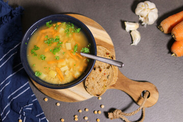Top view of vegetarian yellow peas soup in bowl with slices of olive bread