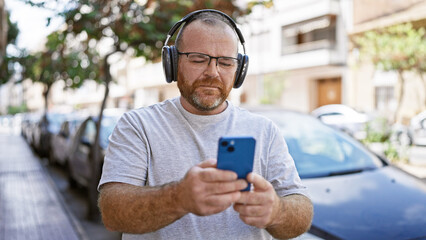 Caucasian man using smartphone wearing headphones at street