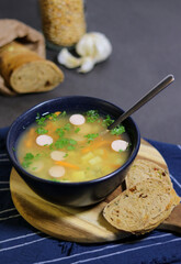 Yellow peas soup with cute sausage in a blue bowl with slices of olive bread