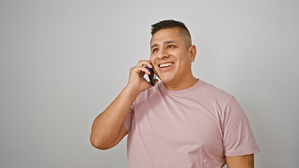 Cool, confident latin young man engaged in a fun phone talk, smiling happily while holding his smartphone, isolated on a white background