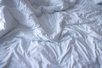 wrinkled white bedding sheets. unmade white bed cover background and texture. soft hotel bed.