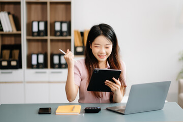 Asian woman sitting at a desk using a laptop computer Navigating Finance and Marketing with Technology