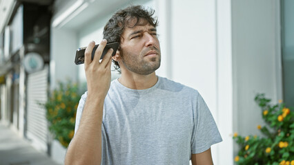 Young man listening to voice message at the street