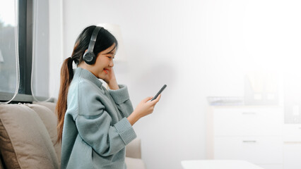 Asian woman using the smartphone and tablet on the sofa at home office.