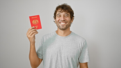 Confident young man exuding joy, proudly flaunts his malaysian passport, standing isolated against...