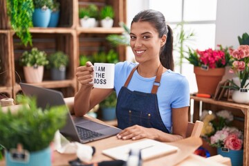 Brunette young woman working at florist shop holding i am the boss cup looking positive and happy standing and smiling with a confident smile showing teeth